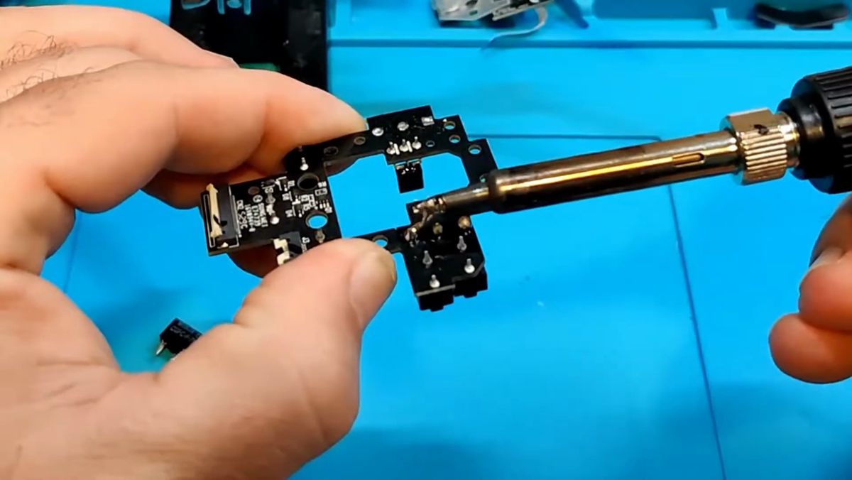 Soldering iron heating the legs of an OMRON switch on the G604 PCB