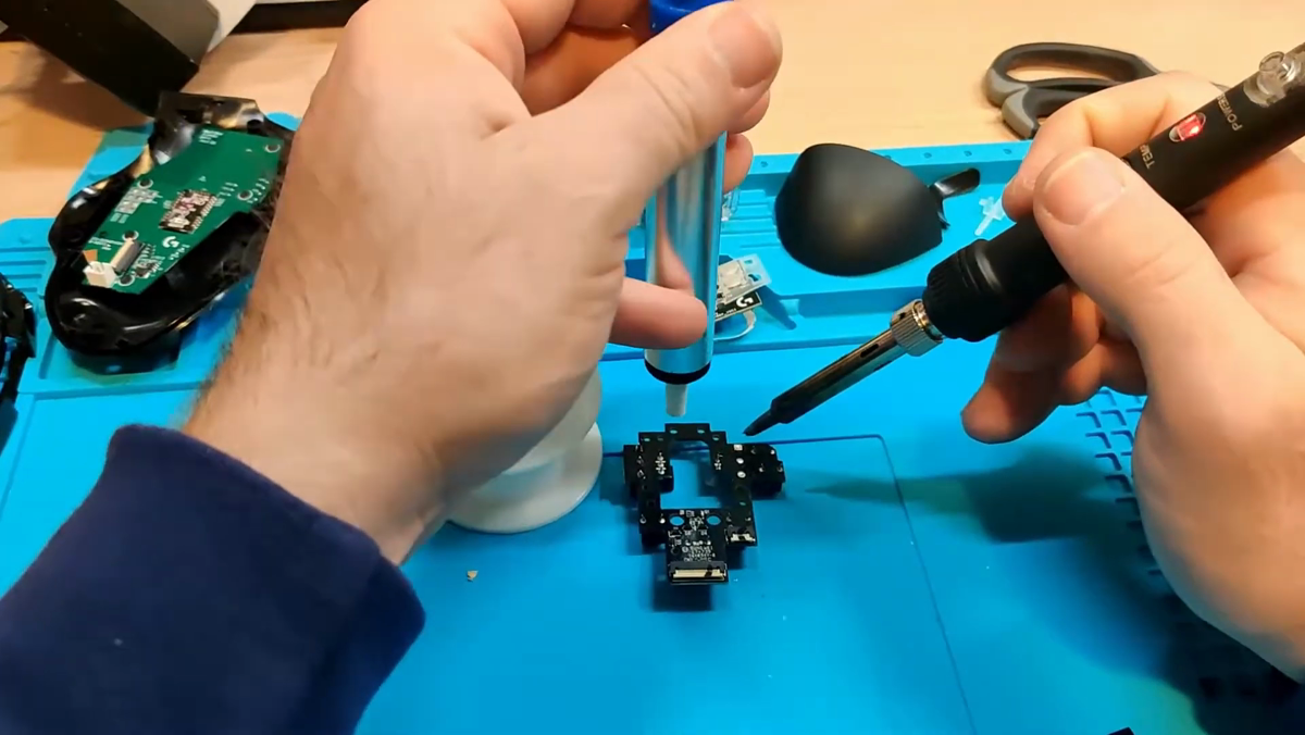 Solder wick being applied to PCB pads on the G604 mouse board