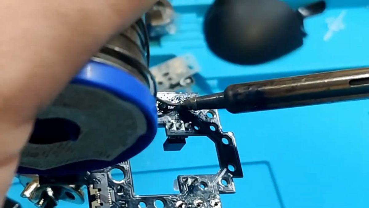 Soldering iron and solder being applied to the legs of a new OMRON switch on the G604 PCB